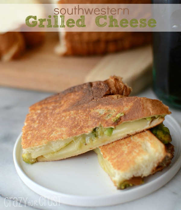 Southwestern grilled cheese sandwich cut in half and placed on white plate on top of marble slab with recipe title on top of image