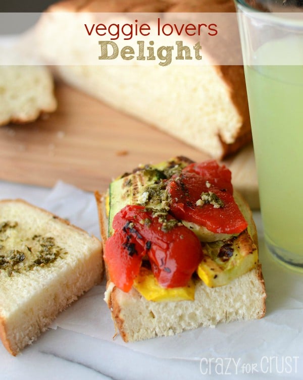 Open faced Veggie Lovers Delight sandwich on parchment paper with loaf of bread and lemonade in background