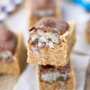 almond joys on peanut butter cookie bars - slices in a stack on parchment
