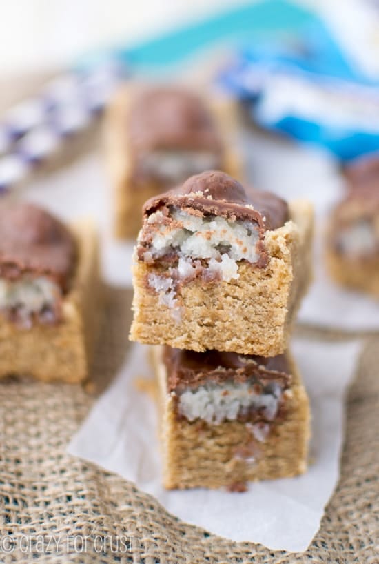 Two Almond Joy Peanut Butter Cookie Bars stacked on top of eachother on a white napkin on burlap