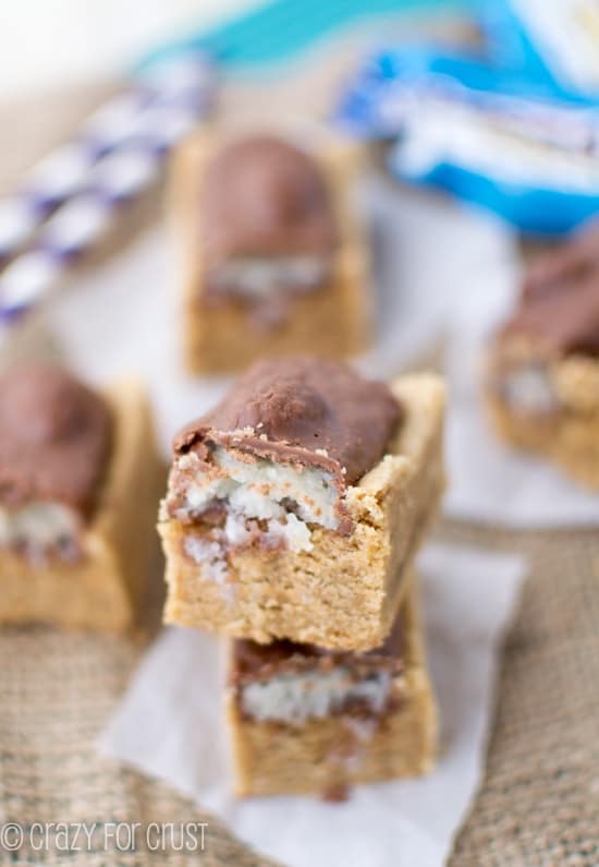 Closeup shot of two Almond Joy Peanut Butter Cookie Bars stacked on top of eachother with more cookie bars in the background