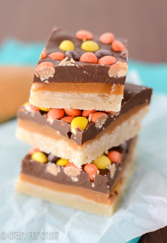 Stack of three Peanut Butter Caramel Shortbread Bars on white parchment paper