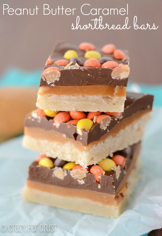 stack of cookie bars with shortbread layer, peanut butter caramel layer, chocolate layer and reese's pieces on top
