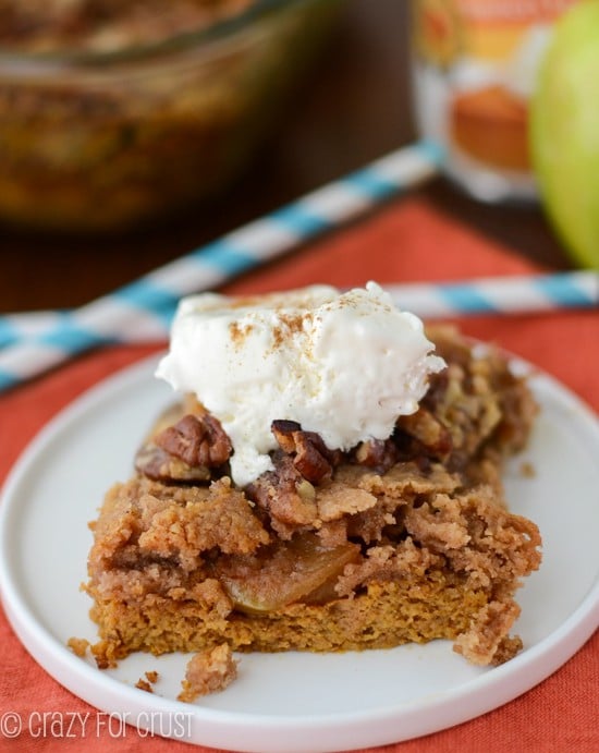 pumpkin apple dump cake slice on white plate with whipped cream