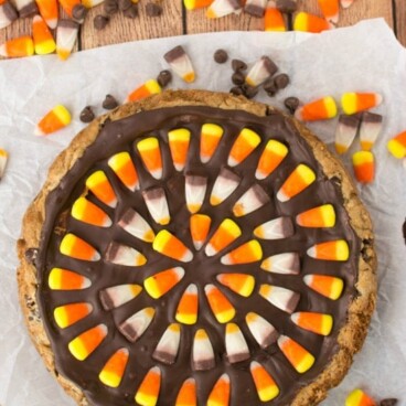 overhead shot of chocolate chip cookie cake topped with chocolate and candy corn patter with candy corn around it