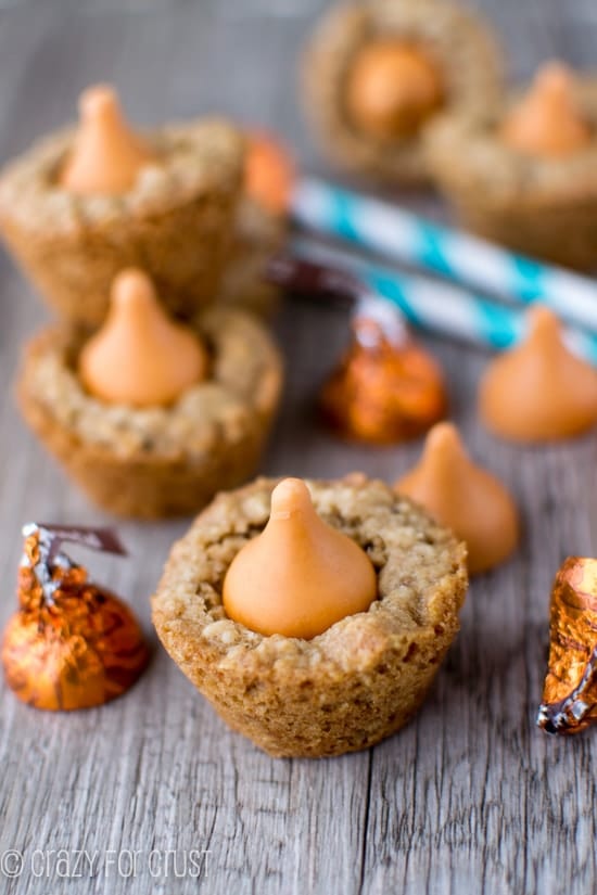 Pumpkin Spice Oatmeal Cookie Cups on a wood table with pumpkin spice hershey kisses and turquoise and white striped straws