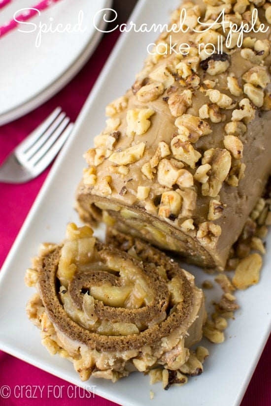 spice cake roll filled with apples and topped with caramel frosting and nuts on white platter with recipe title in text on top of photo