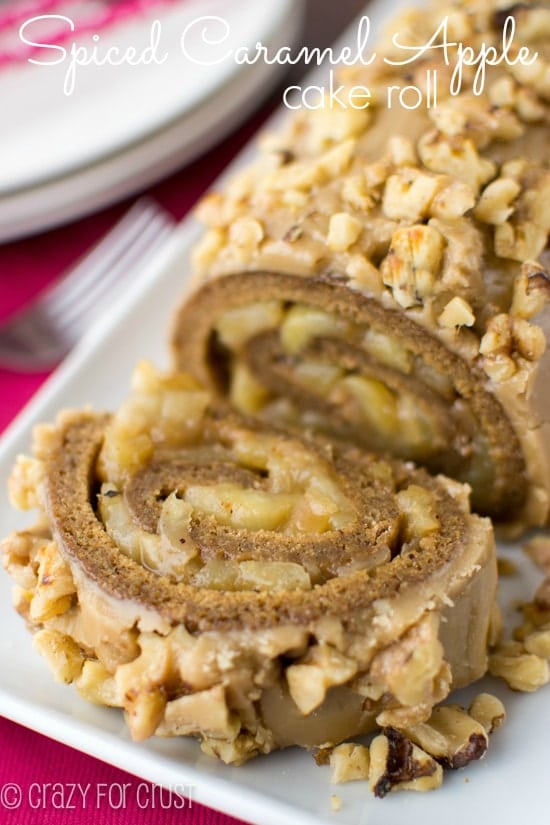 spice cake roll filled with apples and topped with caramel frosting and nuts on white platter