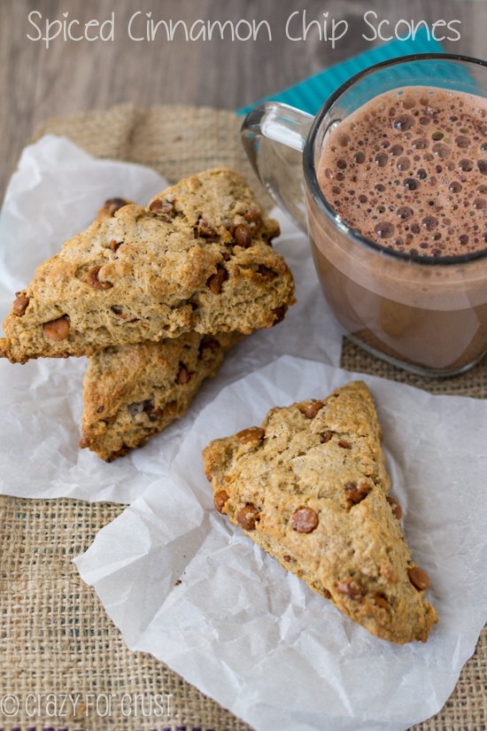 Overhead shot of Spiced Cinnamon Chip Scones on parchment paper on burlap tablecloth with a cup of coffee