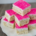 toasted coconut rice krispie treats on white plate with hot pink sugar on top