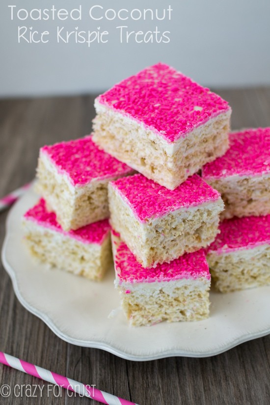 toasted coconut rice krispie treats on white plate with hot pink sugar on top