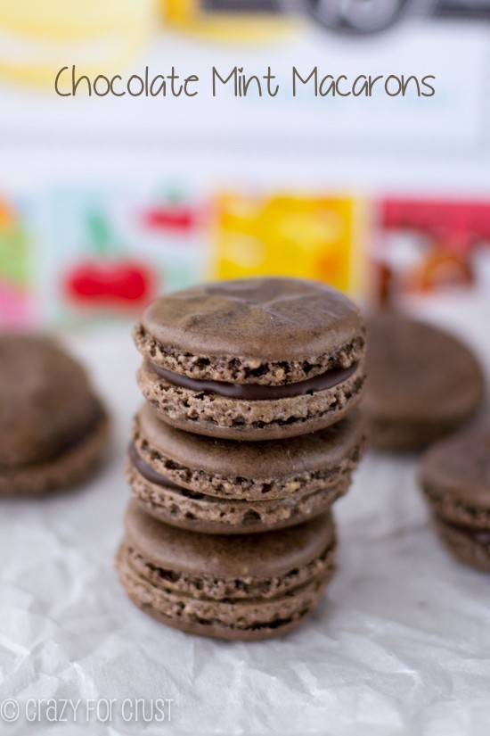 Stack of three Chocolate Mint Macarons on white parchment paper with more macarons around it