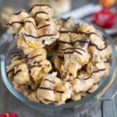 caramel corn coated with peanut butter white chocolate in clear dish with candy around