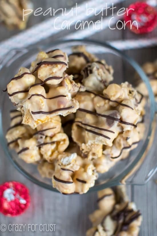 caramel corn coated with peanut butter white chocolate in clear dish with candy around