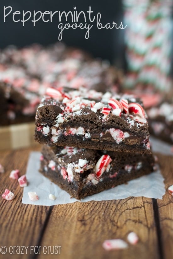 Side view showing two Peppermint Gooey Bars stacked with candy cane pieces inside and on top with recipe title in top left hand corner
