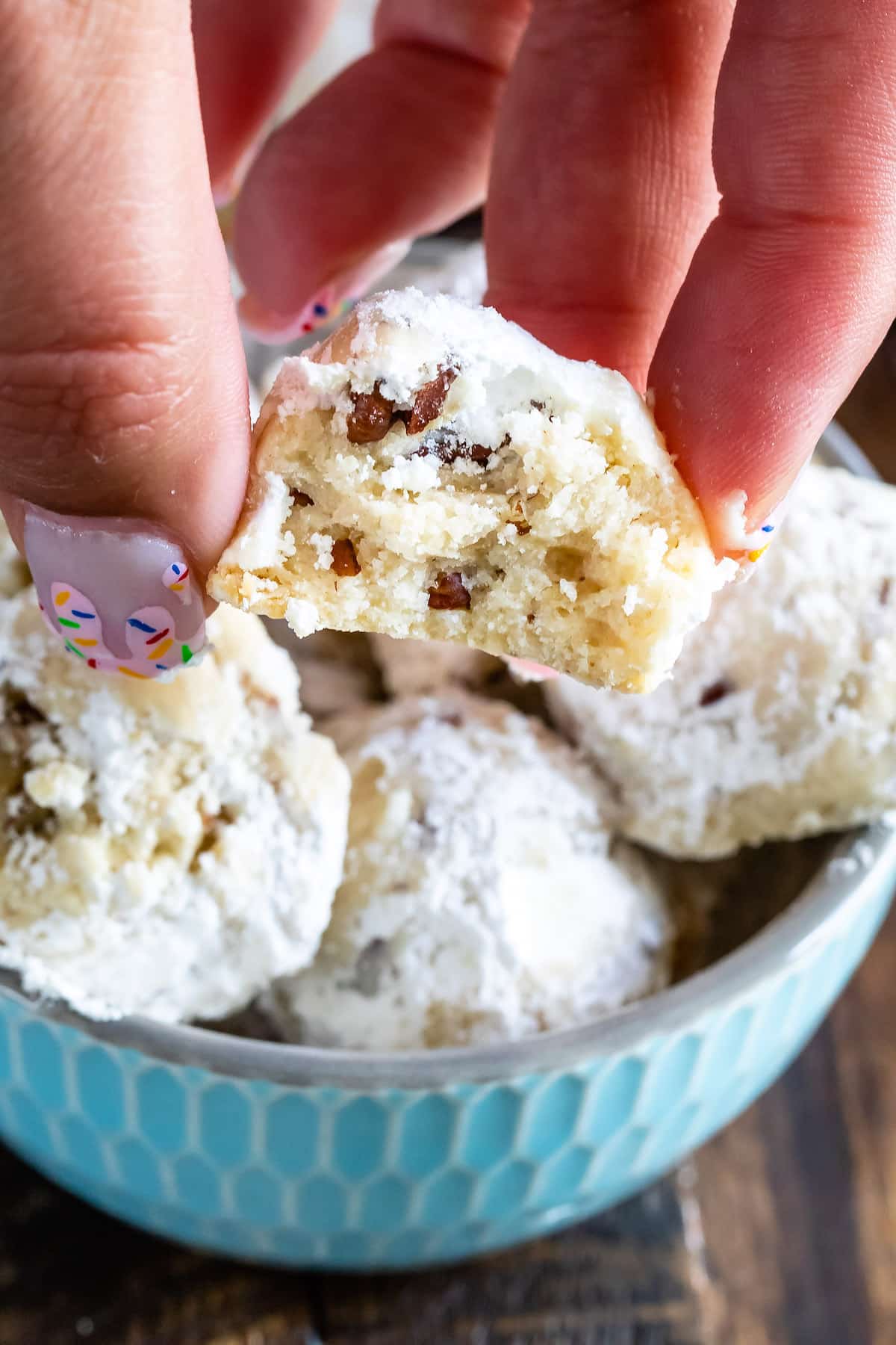 cookies in a bowl with hand holding one cut in half