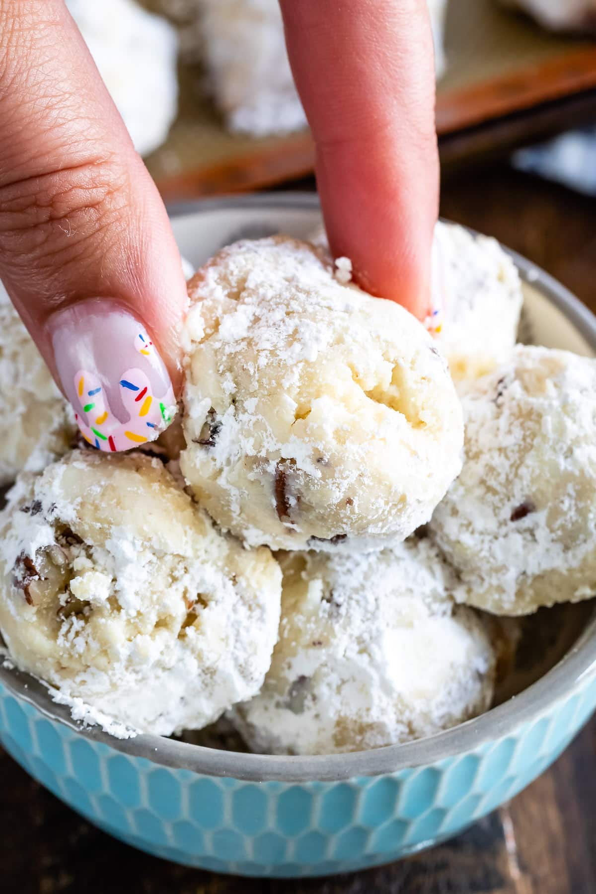 cookies in a bowl with hand holding one