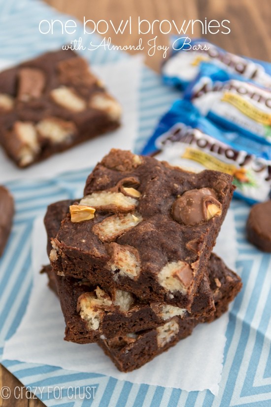 Stack of one bowl candy bar brownies with almond joy on parchment paper with title