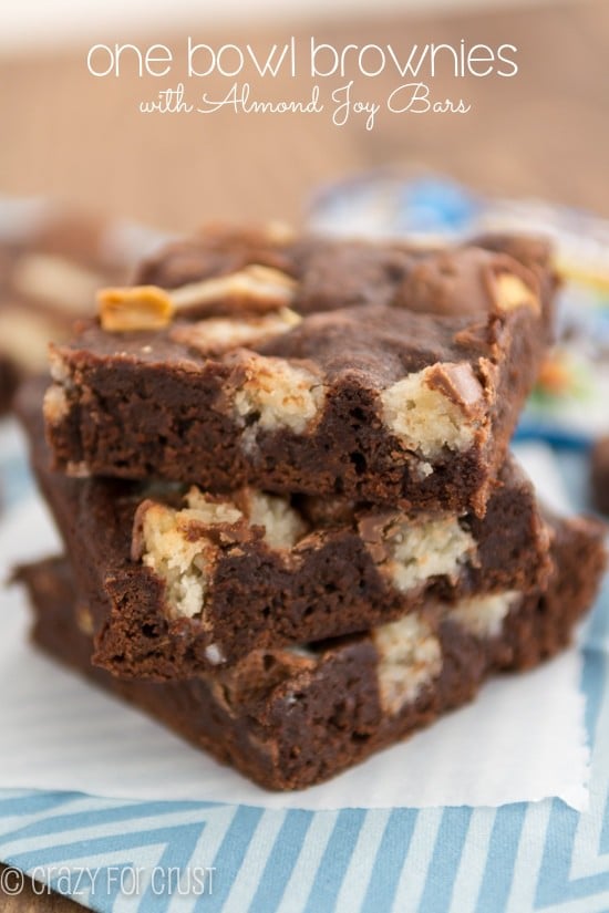 Stack of one bowl candy bar brownies with almond joy on parchment paper with title