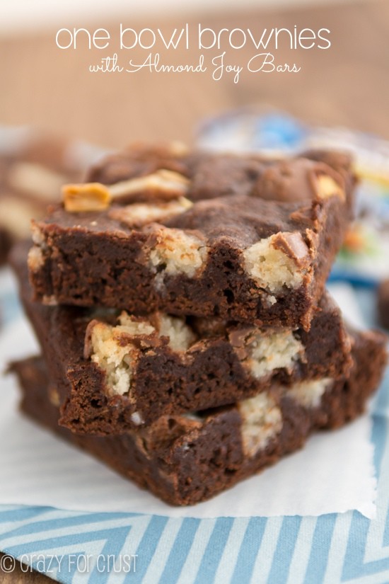 Stack of one bowl candy bar brownies with almond joy on parchment paper with title