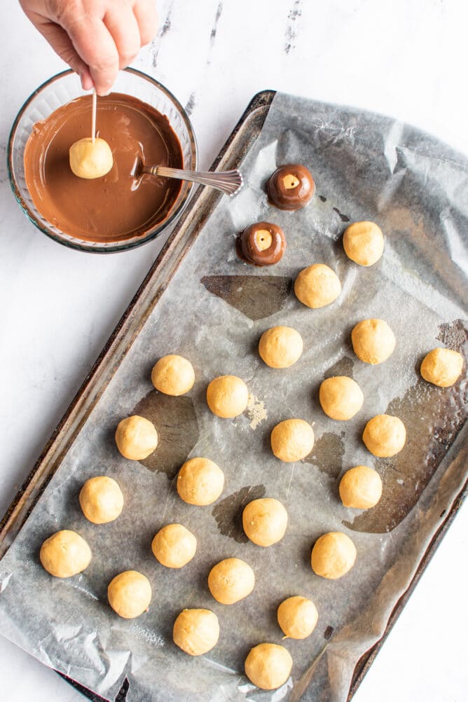 truffles on cookie sheet with bowl of chocolate