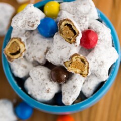 muddy buddies made with peanut butter pretzels and M&Ms in a blue dish