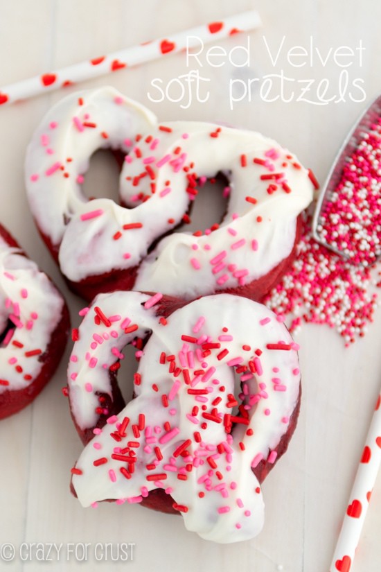 Overhead shot of soft pretzel made with red velvet with frosting and sprinkles and recipe title on top of image