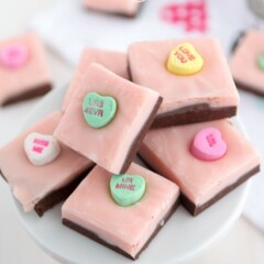stack of valentine fudge with chocolate and pink layer and conversation hearts on white plate