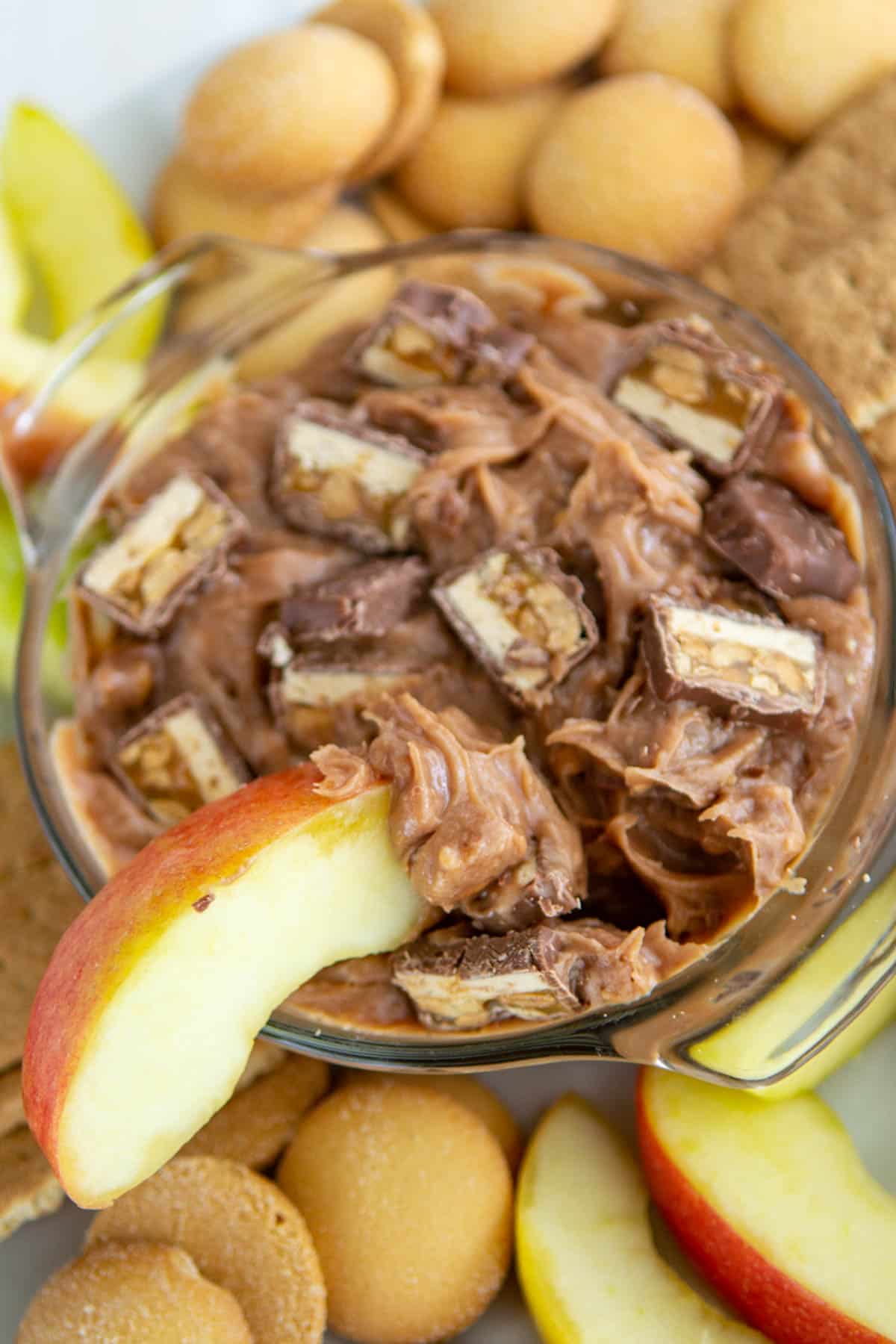 bowl of dip with snickers and an apple slice