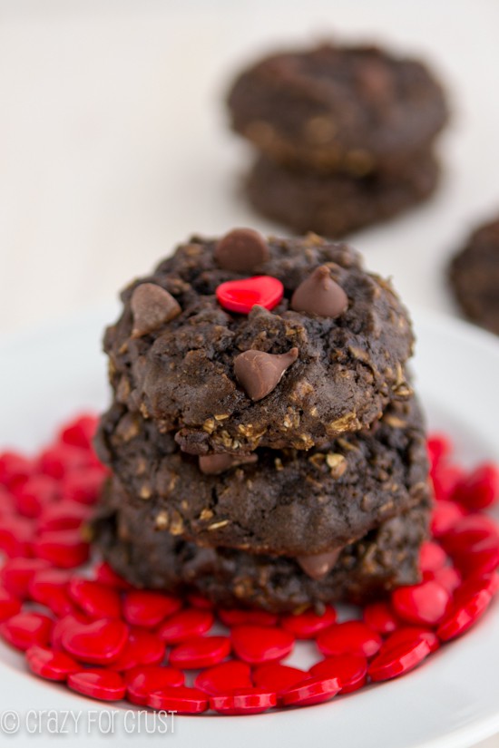 Heart Healthier Chocolate Oatmeal Cookies stacked on a white plate with red heart shaped candies