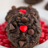chocolate oatmeal cookie with red heart sprinkle on white plate with more sprinkles