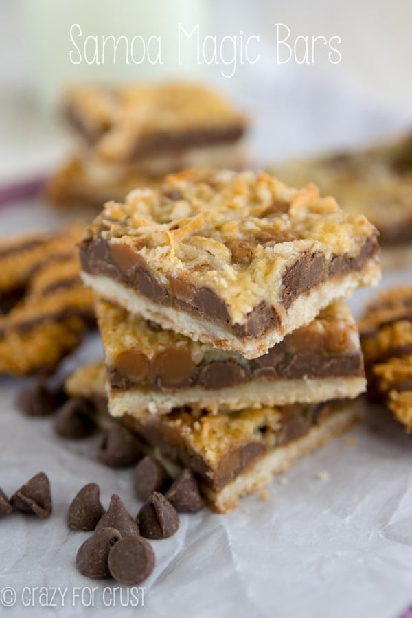 Stack of Samoa Magic Bars on parchment paper with chocolate chips around them