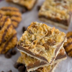 magic cookie bars in a stack with chocolate center and coconut caramel top