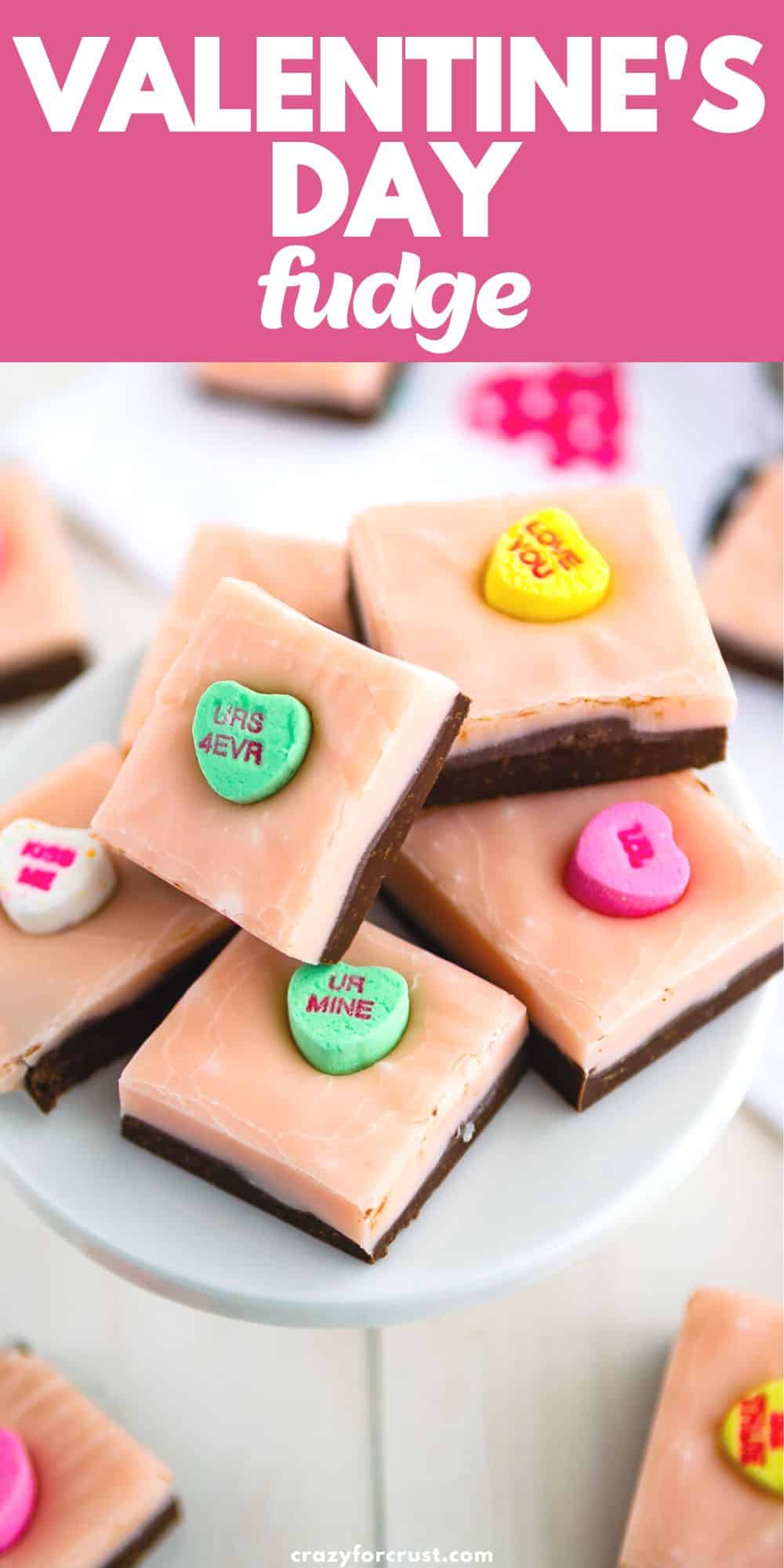 stack of pink and chocolate layered fudge with conversation hearts on white cake stand