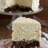 slice of cake with brownie layer and two white layers on pink plate