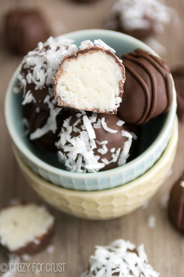 coconut truffle cut in half on stack of truffles in bowl