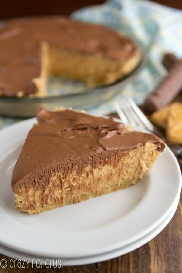 Slice of peanut butter twix pie on a white plate with a fork.