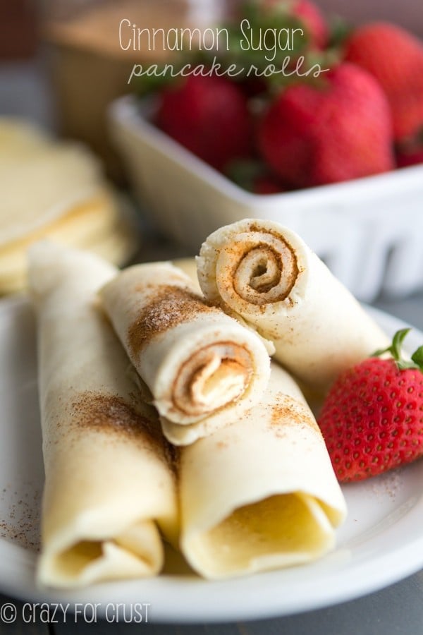 Cinnamon Sugar Pancake Rolls sitting on a white plate with a strawberry 