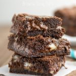 Easy Brownie Gooey Bars stacked on parchment paper with brown background
