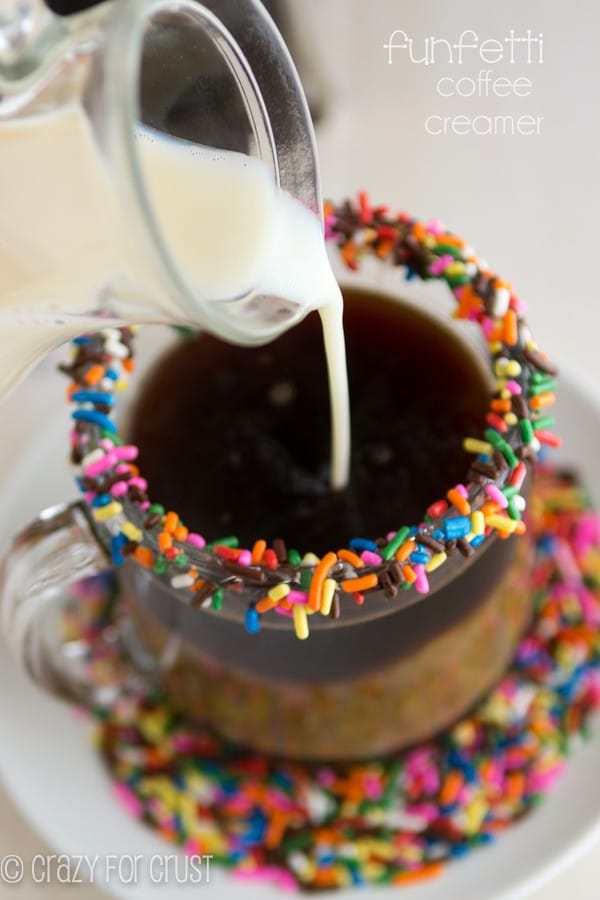 Funfetti Coffee Creamer being poured into coffee with sprinkles around the rim of the glass