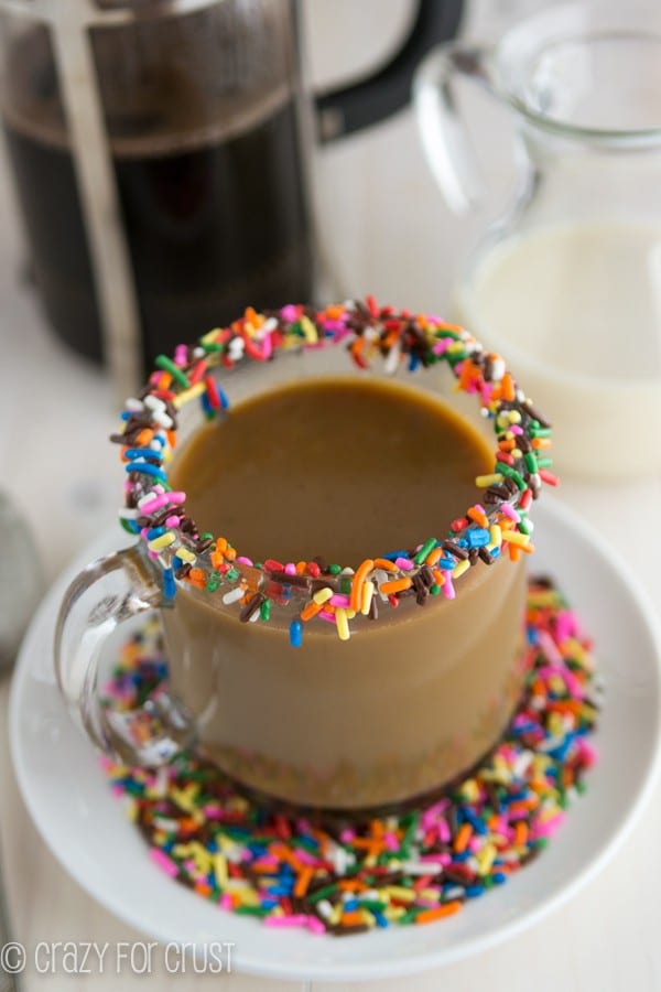 Funfetti Coffee Creamer in a short clear glass with sprinkles around the rim of the glass