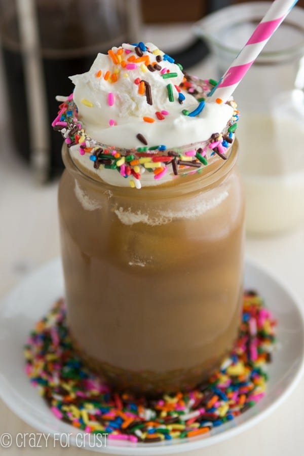Funfetti Coffee Creamer in the coffee with whipped cream on the top and a pink straw 