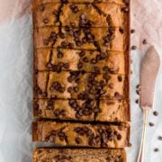 Healthier Banana Bread sitting on parchment paper with knife next to it