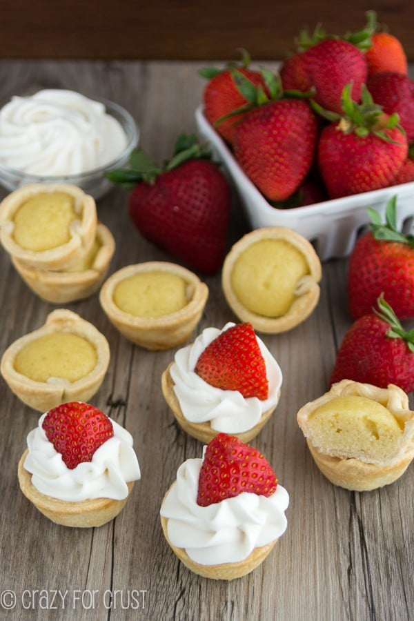 Mini Strawberry Shortcake Pies spread out with strawberries on a wooden board