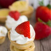 Mini Strawberry Shortcake Pies stacked on top of each other with strawberries in the background