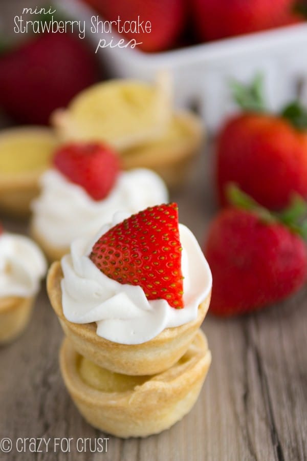 Mini Strawberry Shortcake Pies stacked on top of each other with strawberries in the background 