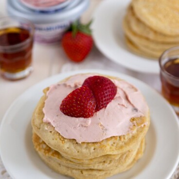 Strawberry Cheesecake Pancakes on a white plate with strawberries on top