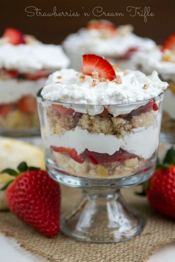 Strawberry Trifles in a trifles glass sitting on a tan towel with strawberries around 