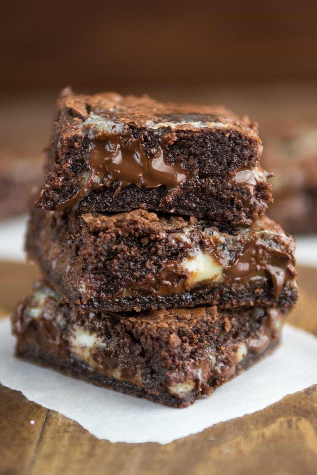 Easy Brownie Gooey Bars stacked on parchment paper with brown background 