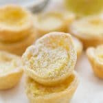 Mini Lemon Chess Pies stacked on top of each other with lemons in the background